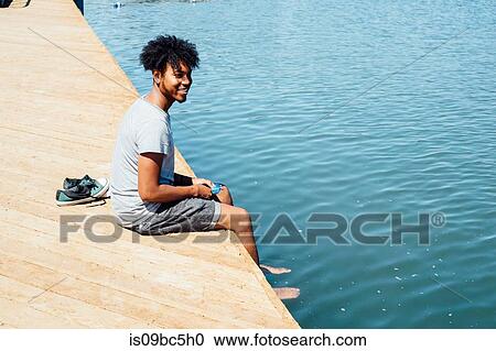Man sitting by edge of water View Large Photo Image Stock Image - Man sitting by edge of water. Fotosearch
