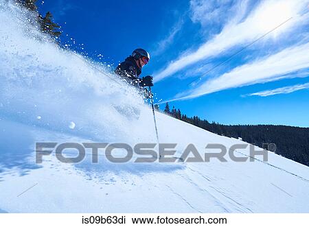Stock Image - Man skiing down deep snow covered mountainside, Aspen, Colorado, USA. Fotosearch