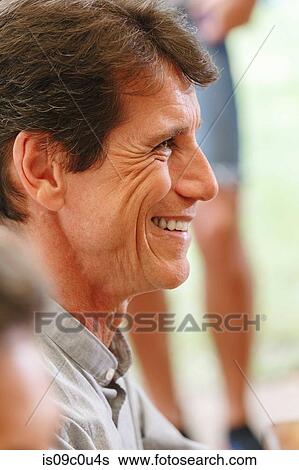 Man smiling happily at gathering View Large Photo Image Stock Photograph - Man smiling happily at gathering. Fotosearch