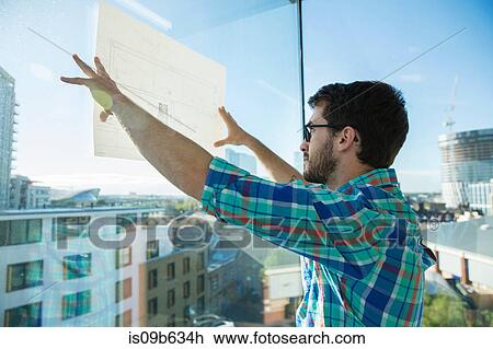 Man, standing beside office window, holding plans up to window View Large Photo Image Stock Image - Man, standing beside office window, holding plans up to window. Fotosearch