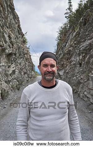 Stock Photo - Man standing between rocky hills, Chitina, Alaska, United States. Fotosearch