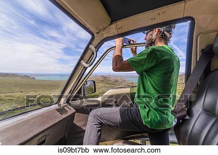 Man standing half out of car door photographing view View Large Photo Image Stock Image - Man standing half out of car door photographing view. Fotosearch