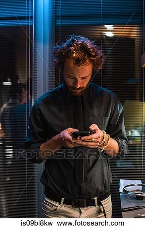 Man texting on mobile phone while at party View Large Photo Image Stock Photo - Man texting on mobile phone while at party. Fotosearch