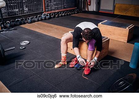 Man tying shoelace in gym View Large Photo Image Stock Photograph - Man tying shoelace in gym. Fotosearch