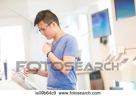 Stock Photo - Man using digital tablet in technology shop. Fotosearch