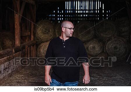Man walking out of barn, hay bales in background View Large Photo Image Picture - Man walking out of barn, hay bales in background. Fotosearch
