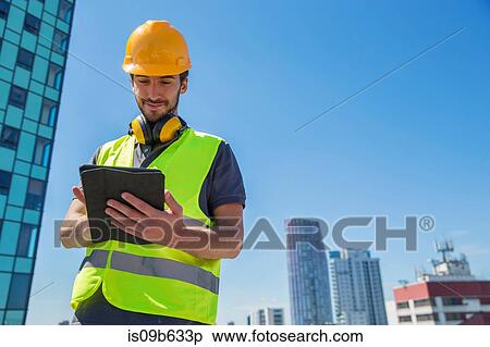 Man wearing hard hat and hi vis vest, outdoors, using digital tablet View Large Photo Image Stock Photography - Man wearing hard hat and hi vis vest, outdoors, using digital tablet. Fotosearch