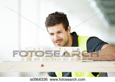 Man wearing hi vis vest, looking at model of building View Large Photo Image Stock Photograph - Man wearing hi vis vest, looking at model of building. Fotosearch