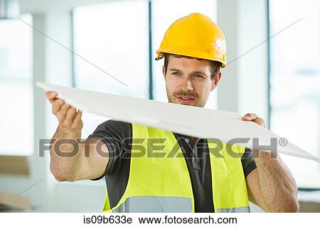 Man wearing hi vis vest, standing in newly constructed space, looking at construction material View Large Photo Image Stock Image - Man wearing hi vis vest, standing in newly constructed space, looking at construction material. Fotosearch