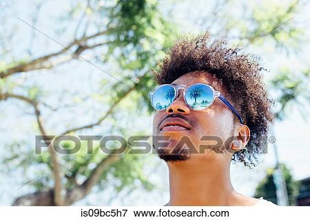 Stock Photo - Man wearing sunglasses, looking up. Fotosearch