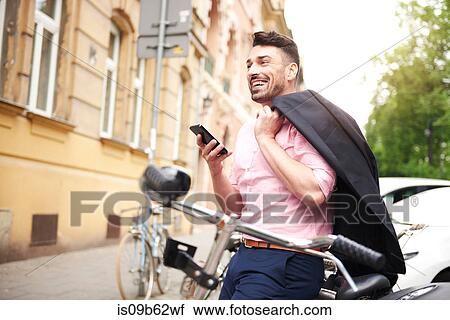 Man with bicycle holding smartphone smiling View Large Photo Image Stock Image - Man with bicycle holding smartphone smiling. Fotosearch