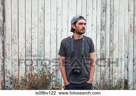 Man with camera, wooden fence in background View Large Photo Image Stock Image - Man with camera, wooden fence in background. Fotosearch