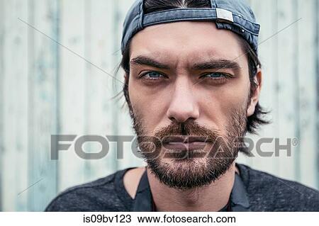 Stock Image - Man with stubble wearing cap back to front. Fotosearch