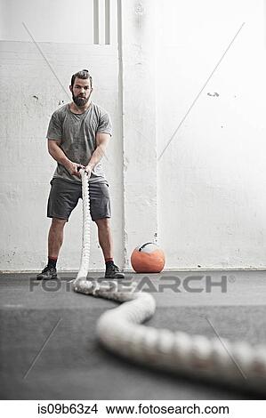Man working out with battle rope in cross training gym View Large Photo Image Picture - Man working out with battle rope in cross training gym. Fotosearch