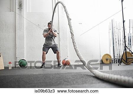 Man working out with battle rope in cross training gym View Large Photo Image Stock Image - Man working out with battle rope in cross training gym. Fotosearch