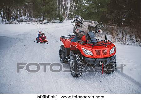 Mature woman driving quad bike, pulling children along on sledge View Large Photo Image Stock Image - Mature woman driving quad bike, pulling children along on sledge. Fotosearch