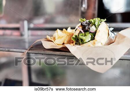 Meal of salad wrap and potato chips on counter View Large Photo Image Stock Photograph - Meal of salad wrap and potato chips on counter. Fotosearch