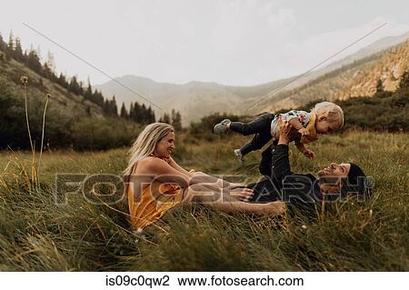 Stock Image - Mid adult couple holding up toddler daughter in rural valley, Mineral King, California, USA. Fotosearch