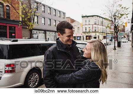 Mid adult couple hugging in street, smiling View Large Photo Image Picture - Mid adult couple hugging in street, smiling. Fotosearch