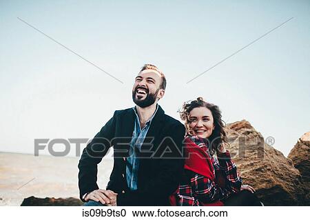 Stock Image - Mid adult couple laughing together on beach, Odessa Oblast, Ukraine. Fotosearch