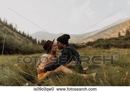 Stock Image - Mid adult couple sitting down hugging in rural valley, Mineral King, California, USA. Fotosearch