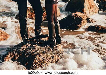 Picture - Mid adult couple standing on sea rock, cropped, Odessa Oblast, Ukraine. Fotosearch