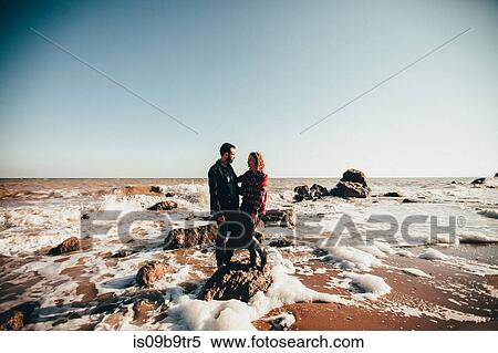 Stock Photography - Mid adult couple standing on sea rock, Odessa Oblast, Ukraine. Fotosearch