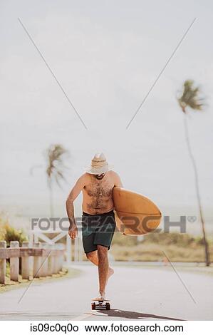 Mid adult male skateboarder carrying surfboard, skateboarding on coastal road, Haiku, Hawaii, USA View Large Photo Image Picture - Mid adult male skateboarder carrying surfboard, skateboarding on coastal road, Haiku, Hawaii, USA. Fotosearch