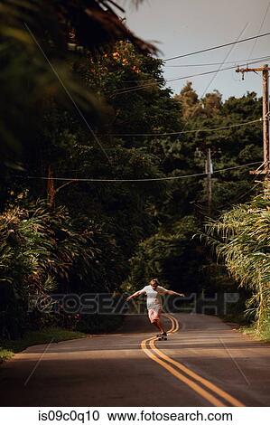 Mid adult male skateboarder skateboarding on centreline along rural road, Haiku, Hawaii, USA View Large Photo Image Stock Image - Mid adult male skateboarder skateboarding on centreline along rural road, Haiku, Hawaii, USA. Fotosearch