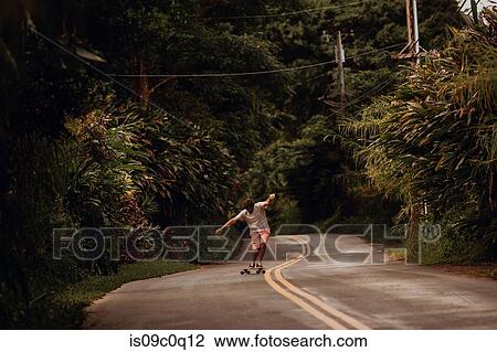 Mid adult male skateboarder skateboarding along rural road with arms outstretched, Haiku, Hawaii, USA View Large Photo Image Stock Image - Mid adult male skateboarder skateboarding along rural road with arms outstretched, Haiku, Hawaii, USA. Fotosearch