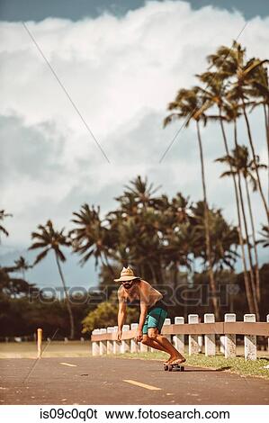 Mid adult male skateboarder wearing straw hat skateboarding on rural road, Haiku, Hawaii, USA View Large Photo Image Stock Photograph - Mid adult male skateboarder wearing straw hat skateboarding on rural road, Haiku, Hawaii, USA. Fotosearch