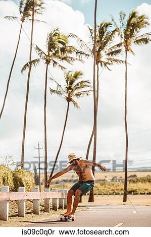 Mid adult male skateboarder wearing straw hat, skateboarding on coastal road, Haiku, Hawaii, USA View Large Photo Image Stock Photography - Mid adult male skateboarder wearing straw hat, skateboarding on coastal road, Haiku, Hawaii, USA. Fotosearch