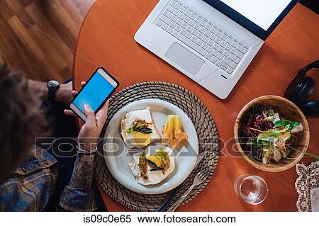 Mid adult man about to eat fried egg meal at table, looking at smartphone, overhead view View Large Photo Image Stock Photography - Mid adult man about to eat fried egg meal at table, looking at smartphone, overhead view. Fotosearch