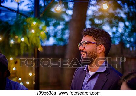Mid adult man at garden party, at dusk, smiling View Large Photo Image Stock Photograph - Mid adult man at garden party, at dusk, smiling. Fotosearch