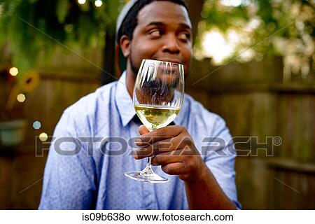 Mid adult man at garden party, holding glass of wine View Large Photo Image Picture - Mid adult man at garden party, holding glass of wine. Fotosearch