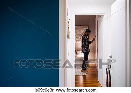Mid adult man getting dressed in bedroom, view from hallway View Large Photo Image Stock Photography - Mid adult man getting dressed in bedroom, view from hallway. Fotosearch