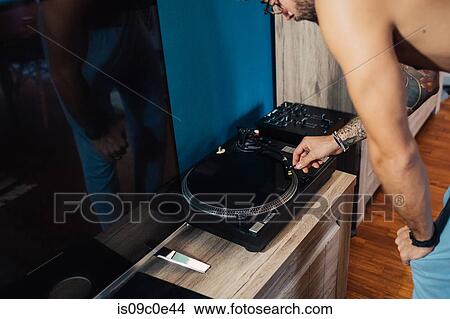 Picture - Mid adult man playing vinyl record on turntable, cropped. Fotosearch