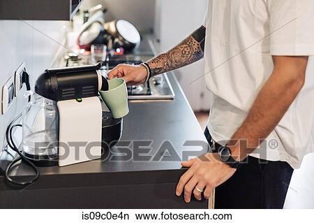 Mid adult man pouring coffee from coffee machine on kitchen counter, mid section View Large Photo Image Picture - Mid adult man pouring coffee from coffee machine on kitchen counter, mid section. Fotosearch