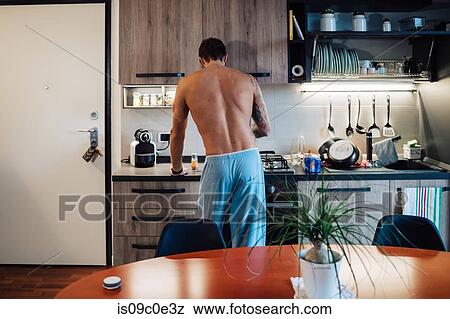 Mid adult man preparing breakfast at kitchen hob, rear view View Large Photo Image Stock Photo - Mid adult man preparing breakfast at kitchen hob, rear view. Fotosearch
