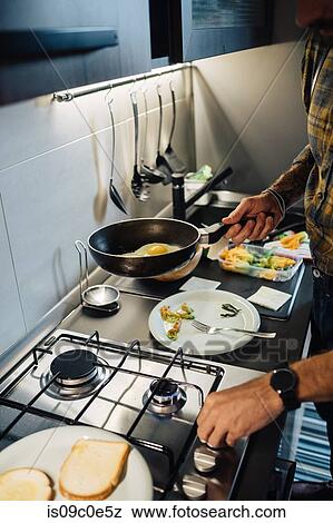 Mid adult man preparing fried eggs at kitchen hob, cropped View Large Photo Image Stock Photo - Mid adult man preparing fried eggs at kitchen hob, cropped. Fotosearch