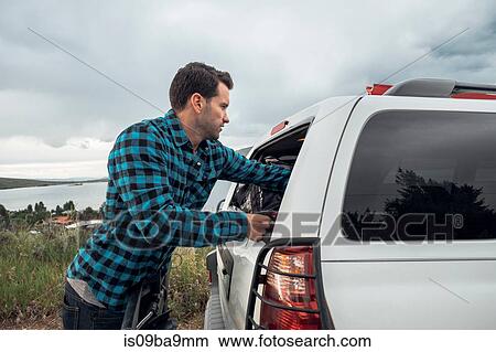 Mid adult man reaching into window of parked car, Silverthorne, Colorado, USA View Large Photo Image Picture - Mid adult man reaching into window of parked car, Silverthorne, Colorado, USA. Fotosearch