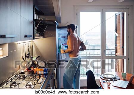 Mid adult man removing bottled water from fridge View Large Photo Image Stock Image - Mid adult man removing bottled water from fridge. Fotosearch