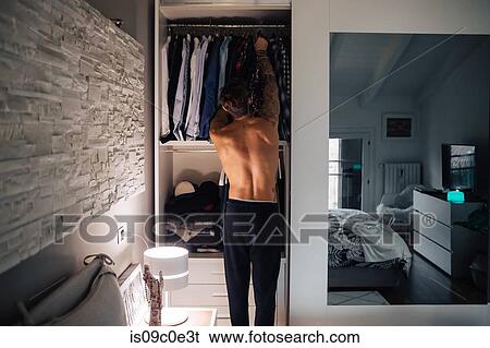 Mid adult man selecting shirt from wardrobe, rear view View Large Photo Image Stock Photograph - Mid adult man selecting shirt from wardrobe, rear view. Fotosearch