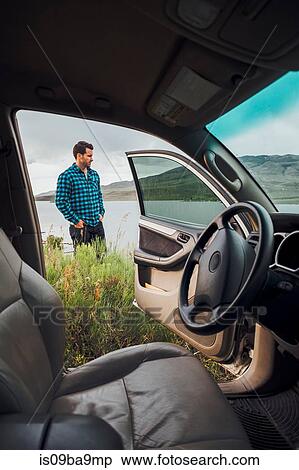 Mid adult man standing beside Dillon Reservoir, view through parked car, Silverthorne, Colorado, USA View Large Photo Image Stock Photography - Mid adult man standing beside Dillon Reservoir, view through parked car, Silverthorne, Colorado, USA. Fotosearch