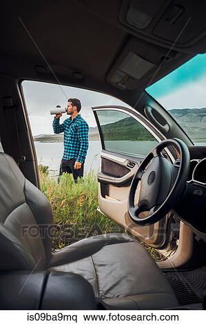 Mid adult man standing beside Dillon Reservoir, drinking from water bottle, view through parked car, Silverthorne, Colorado, USA View Large Photo Image Stock Photography - Mid adult man standing beside Dillon Reservoir, drinking from water bottle, view through parked car, Silverthorne, Colorado, USA. Fotosearch