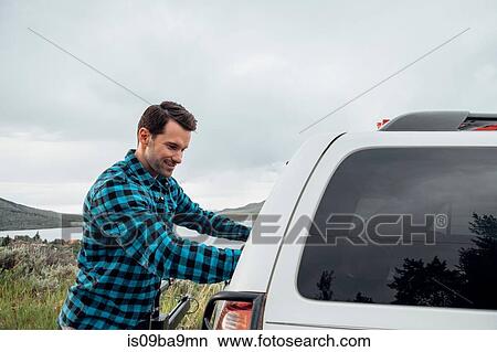Mid adult man standing beside parked car, Silverthorne, Colorado, USA View Large Photo Image Picture - Mid adult man standing beside parked car, Silverthorne, Colorado, USA. Fotosearch