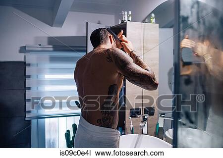 Mid adult man with tattoos combing hair at bathroom mirror View Large Photo Image Stock Image - Mid adult man with tattoos combing hair at bathroom mirror. Fotosearch