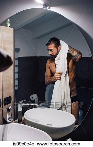 Mid adult man with tattoos drying hair at bathroom mirror, mirror image View Large Photo Image Stock Photography - Mid adult man with tattoos drying hair at bathroom mirror, mirror image. Fotosearch