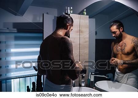 Mid adult man with tattoos getting ready at bathroom mirror View Large Photo Image Picture - Mid adult man with tattoos getting ready at bathroom mirror. Fotosearch