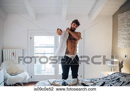 Mid adult man with tattoos putting on shirt in bedroom View Large Photo Image Stock Image - Mid adult man with tattoos putting on shirt in bedroom. Fotosearch